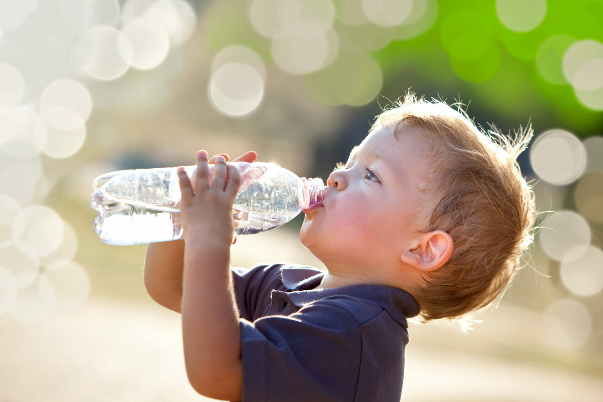 a child drinking water out of a plastic bottle