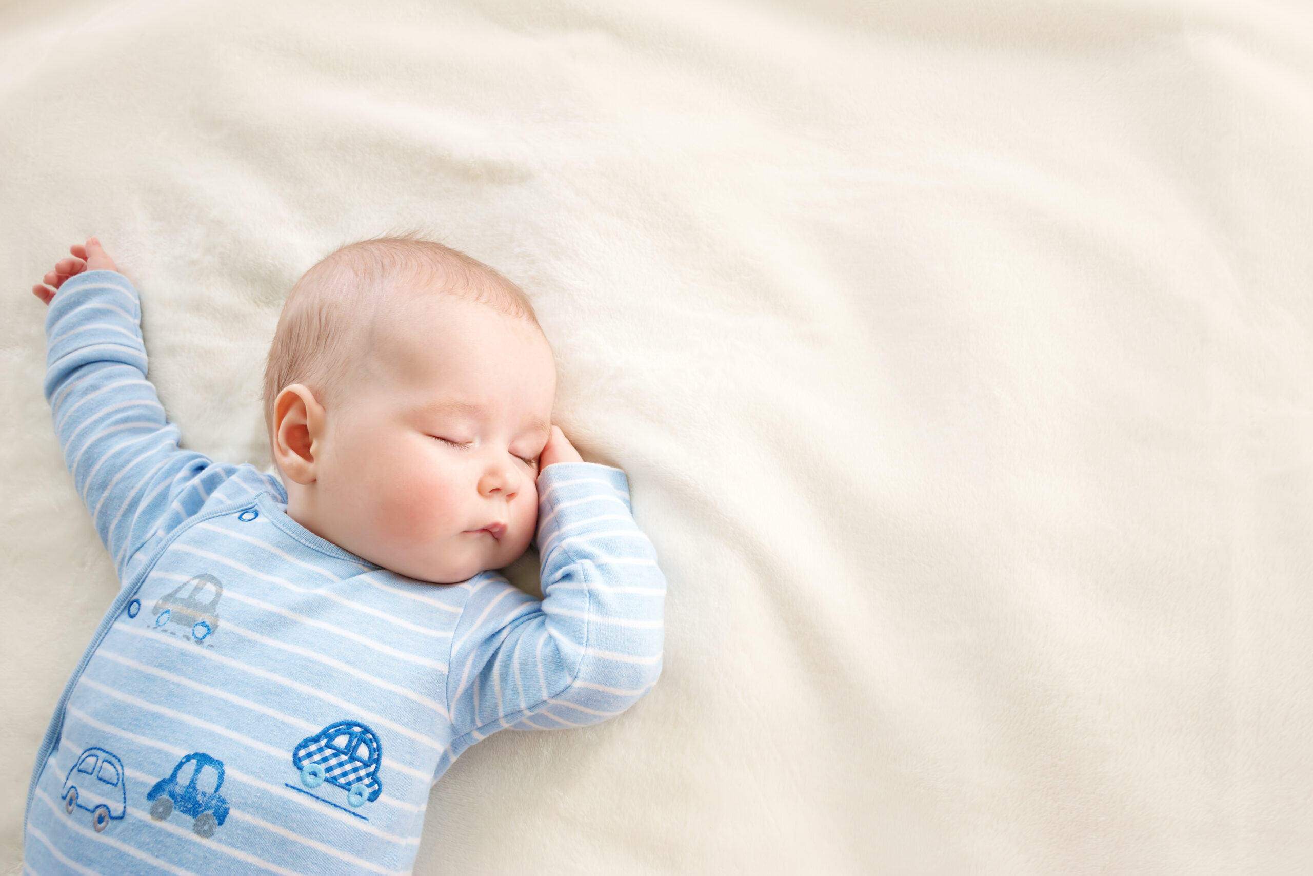 little boy sleeping on soft white blanket