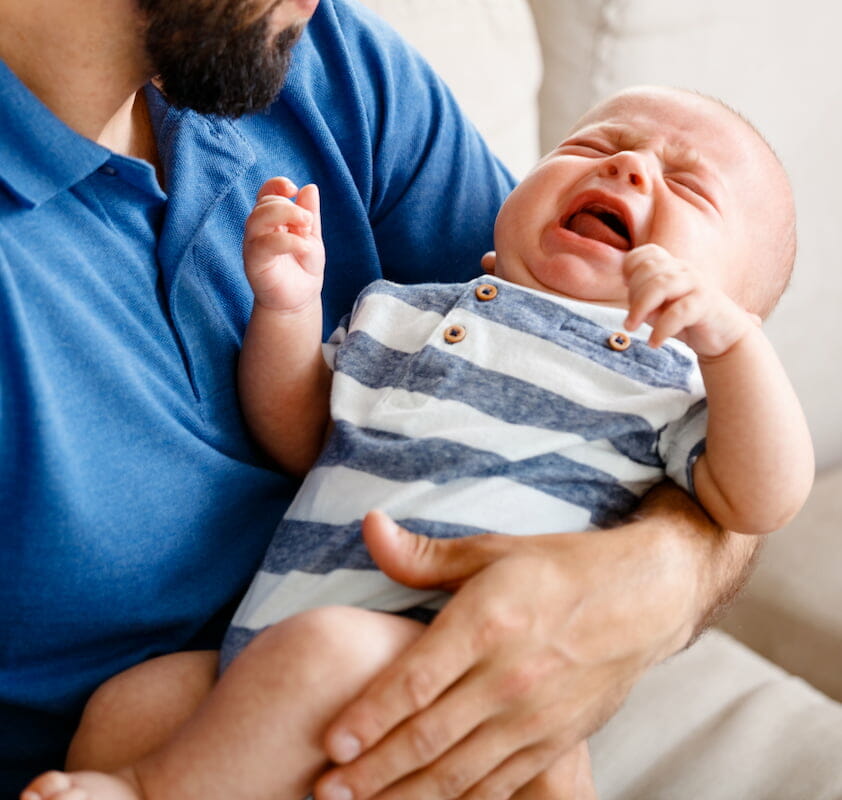 a baby crying in their father's arms