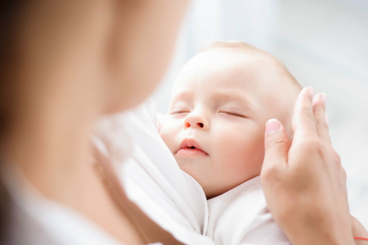 A baby sleeping in their mother's arms
