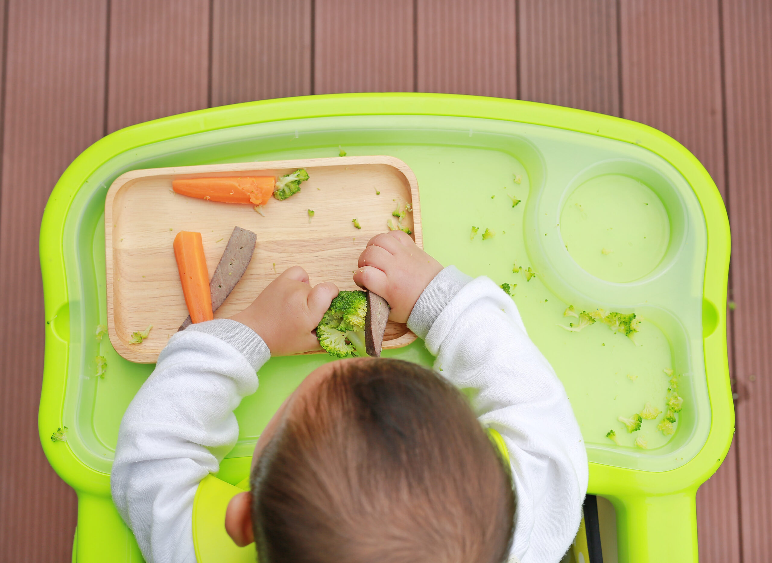 Top view of infant baby eating by Baby Led Weaning (BLW). Finger foods concept.