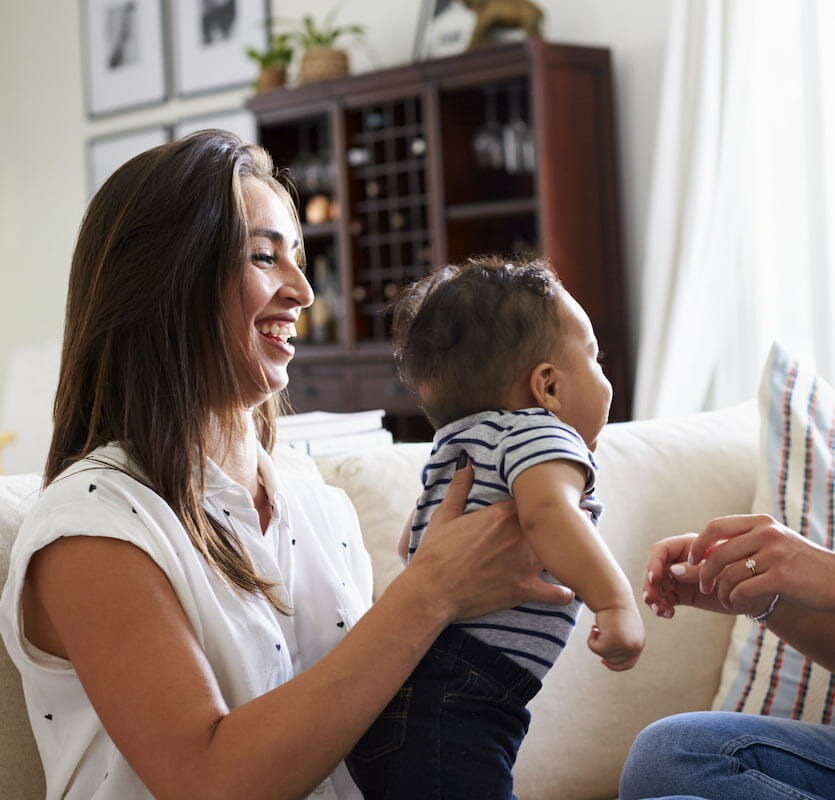 A mother smiling whilst holding her child