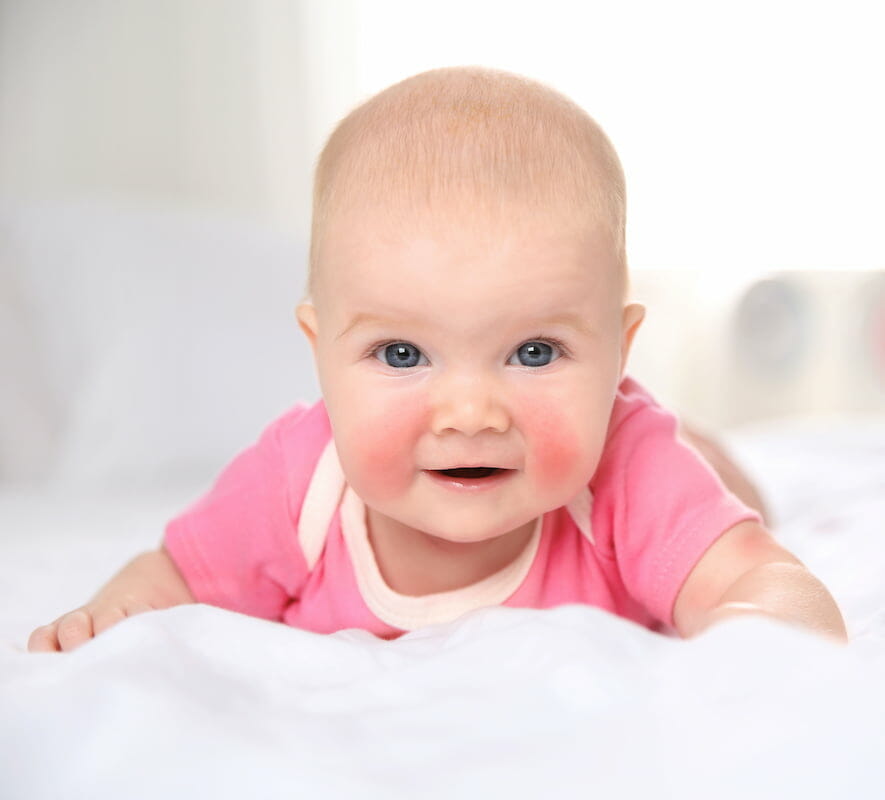 a baby with rosy cheeks lying on their front