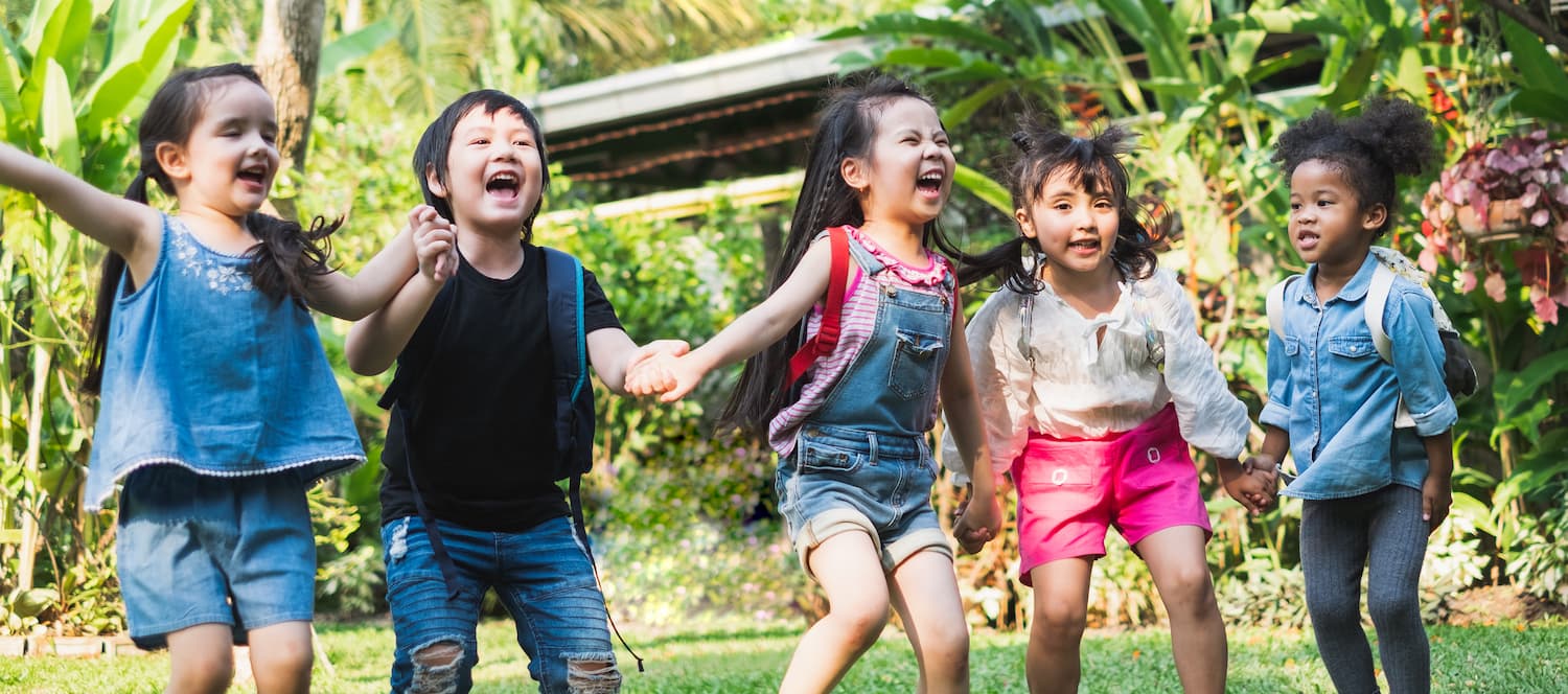 5 children in a line holding hands and laughing