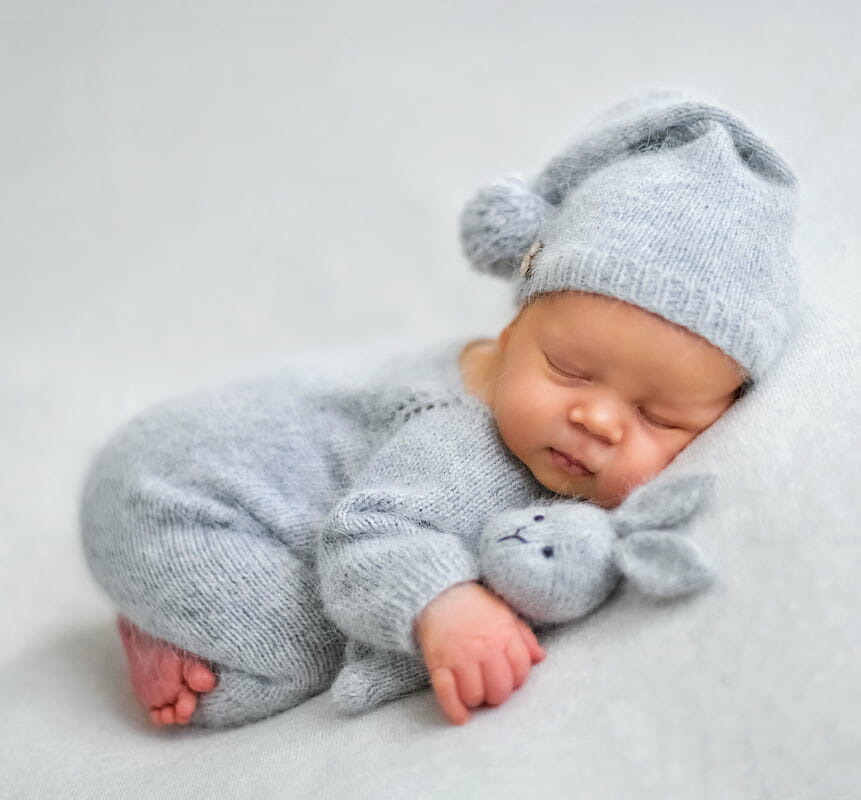 a newborn sleeping with a stuffed rabbit