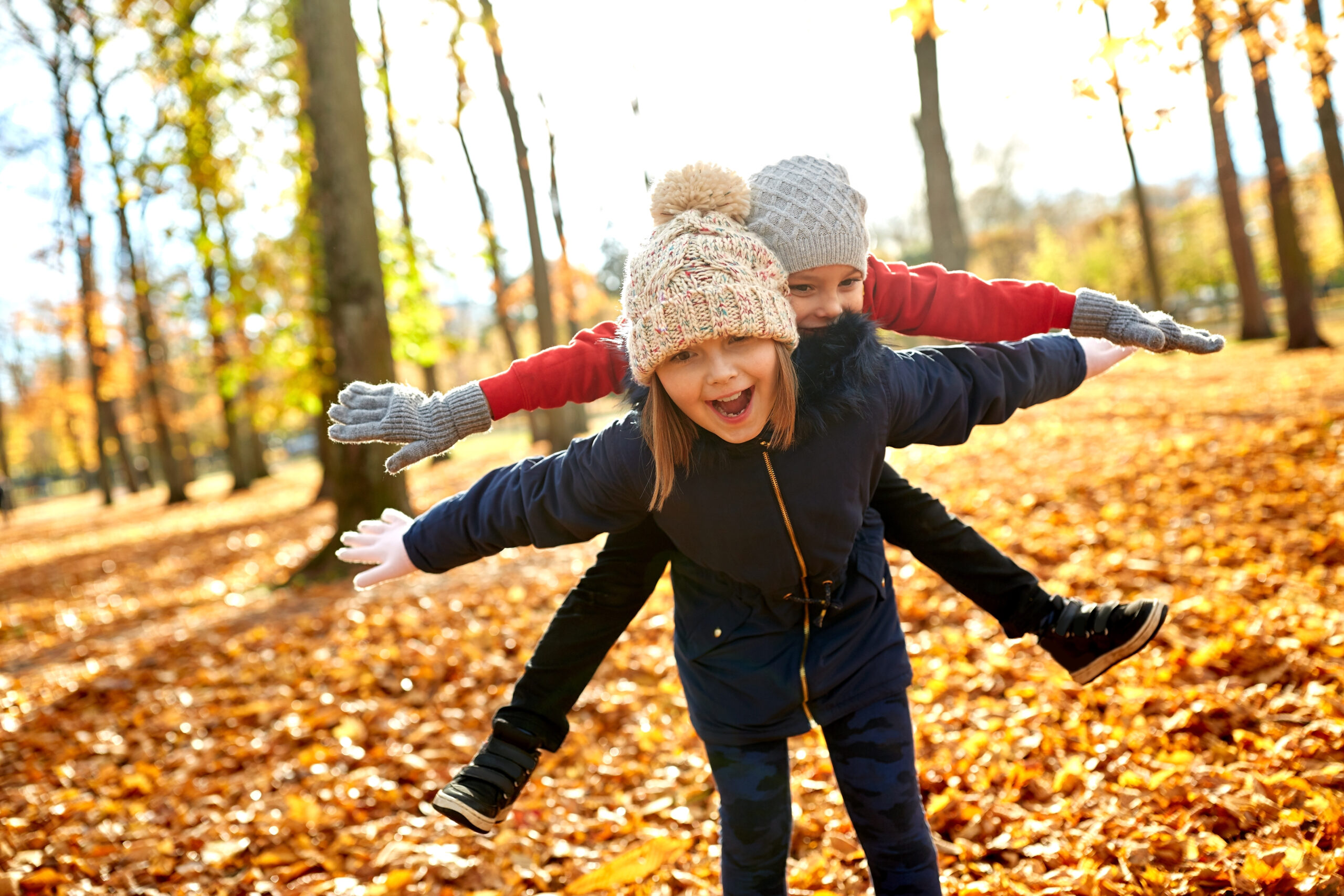 childhood, season and people concept - happy children having fun at autumn park