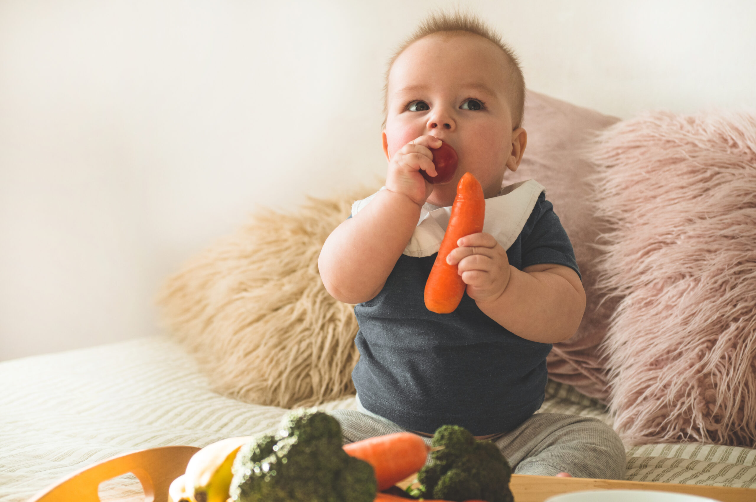 First solid food for young kid. Fresh organic carrot for vegetable lunch. Baby weaning.