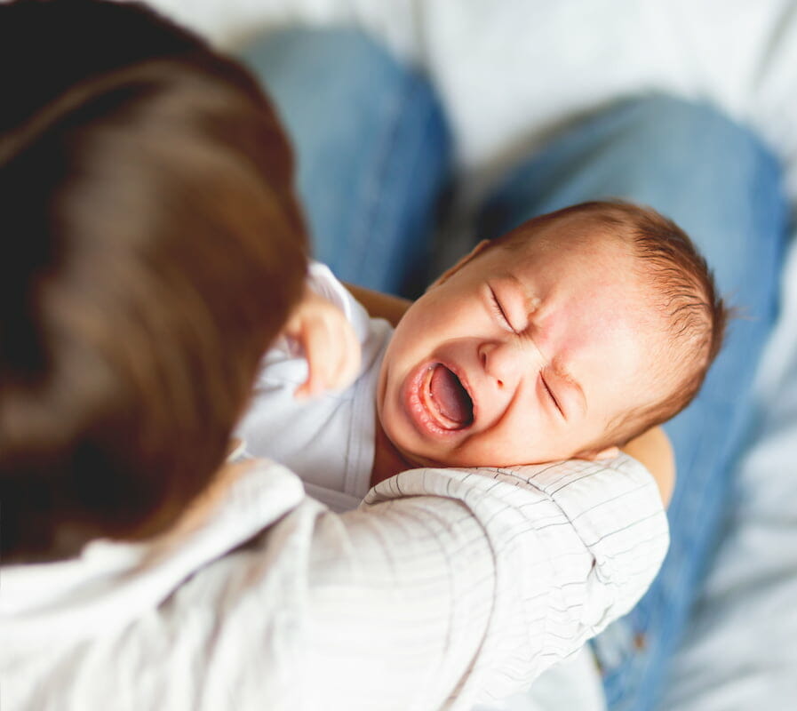 a baby crying in their mother's arms