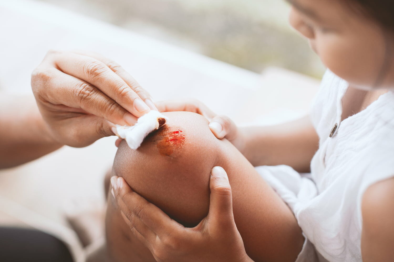 a person tending to a child's grazed knee