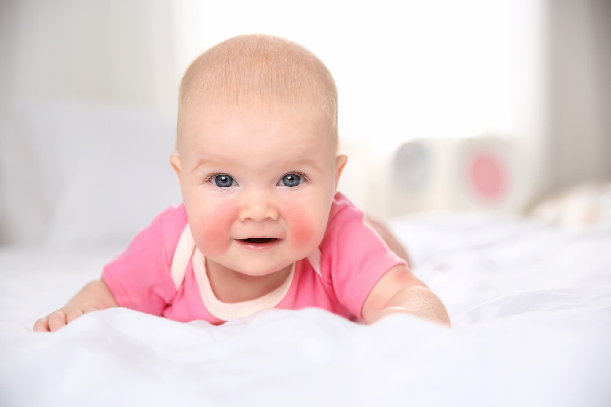 A baby with rosey red cheeks staring at the camera