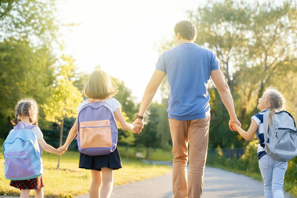 Parent and pupils walking to school hand in hand.