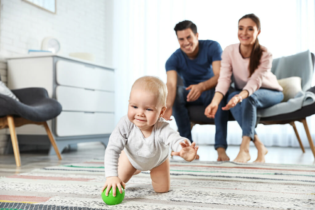 Adorable little baby crawling near parents at home