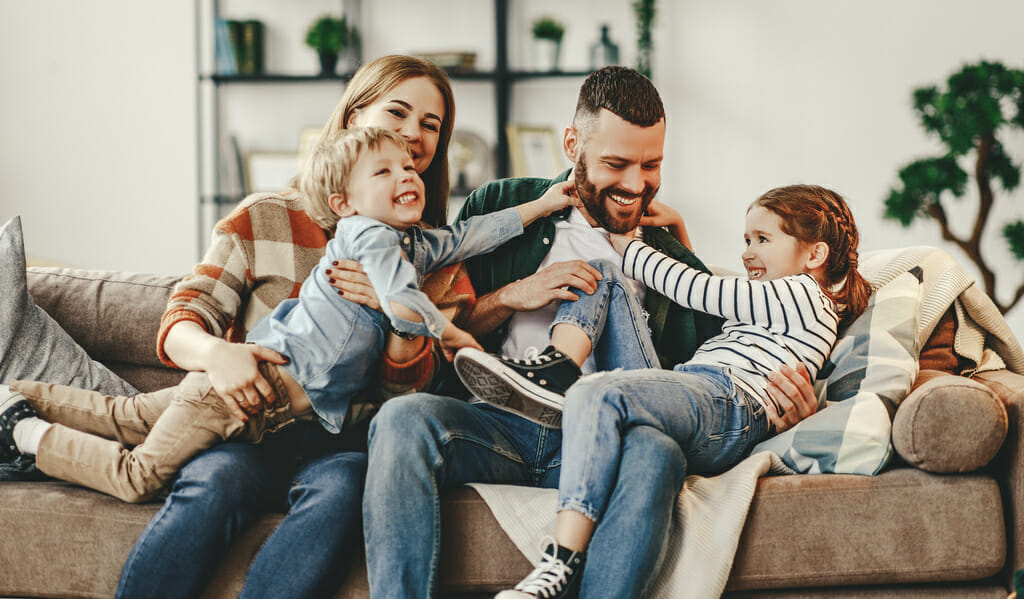 happy family mother father and kids at home playing on the sofa